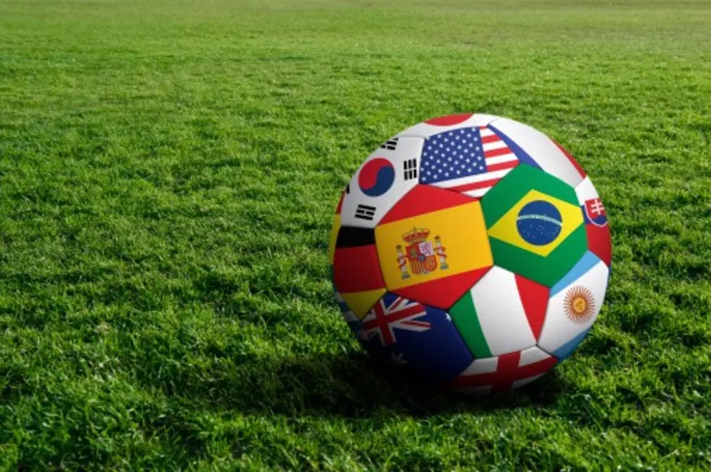 Ballon de football avec drapeaux internationaux sur une pelouse