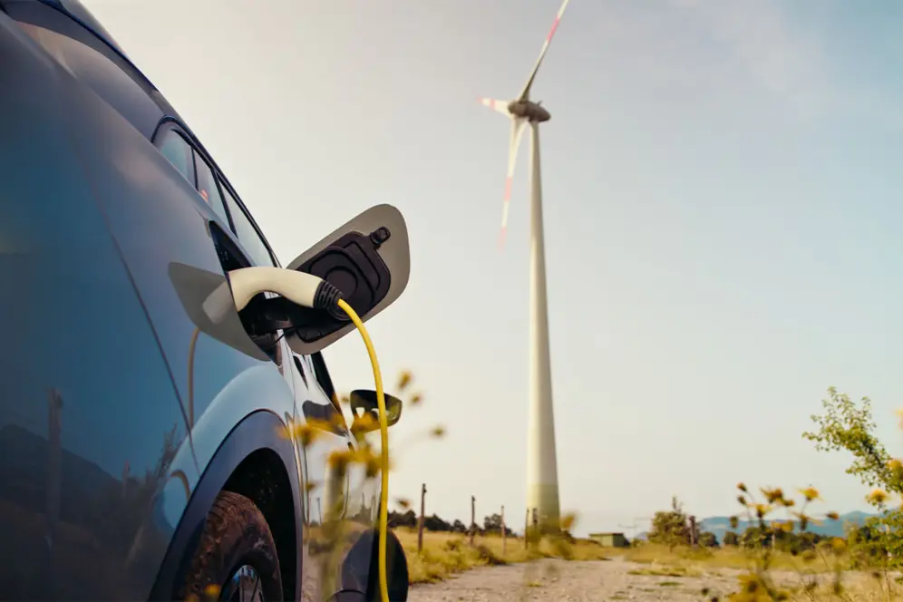 Une voiture électrique en charge devant une éolienne