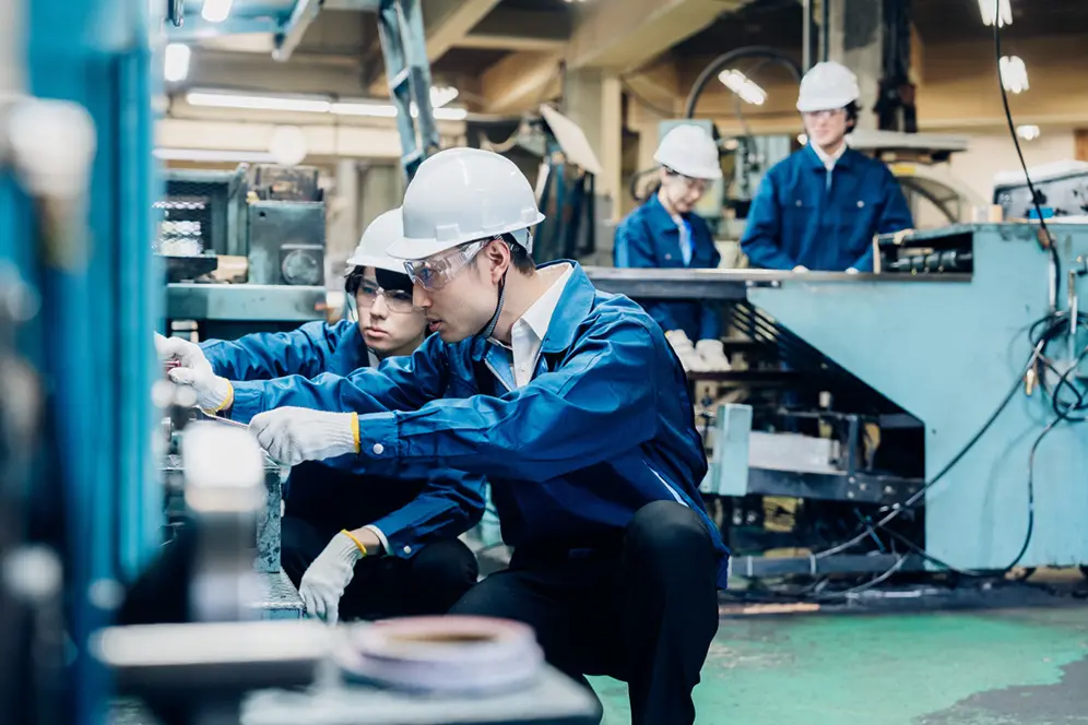 Un maître d'apprentissage formant un apprenti aux mesures de sécurité à effectuer dans un atelier.