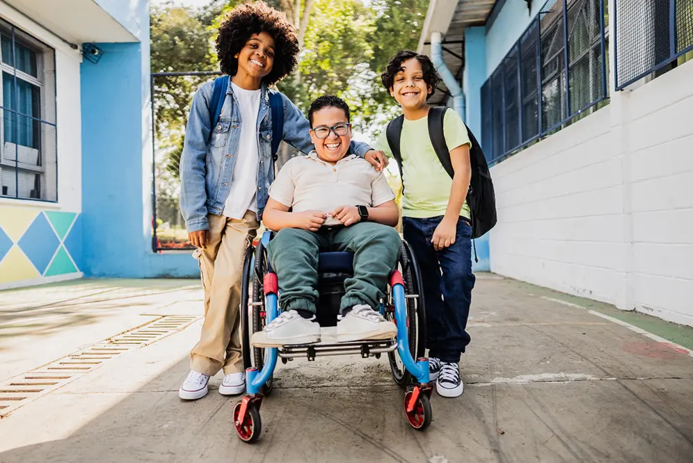 3 jeunes : 1 en fauteuil roulant et deux débout de part et d'autre du fauteuil