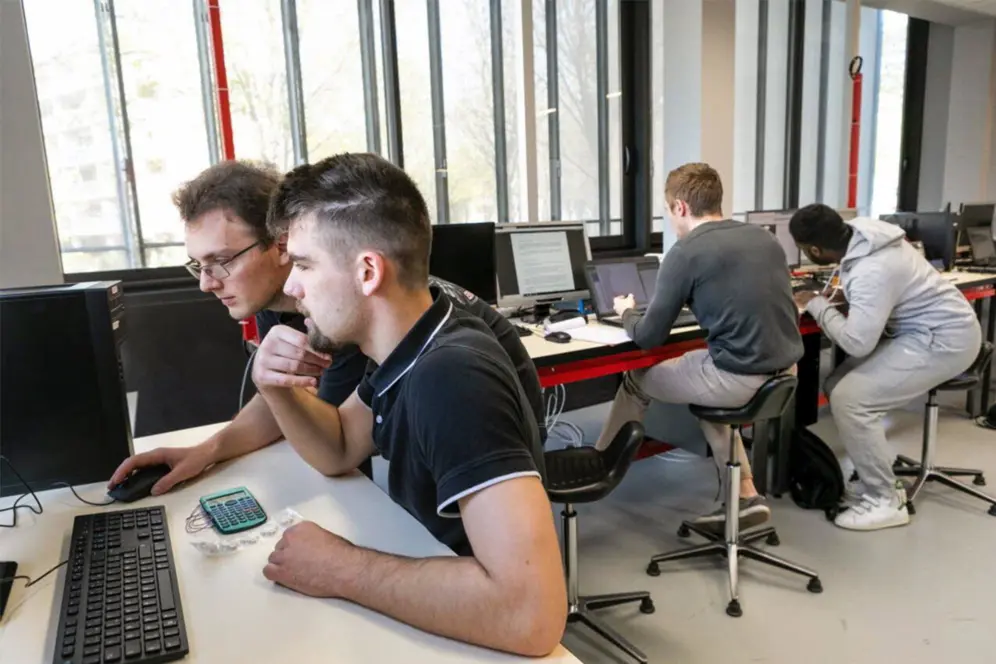 4 jeunes hommes devant des ordinateurs