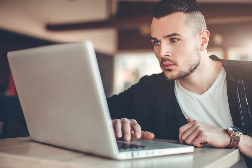 Un étudiant recherchant un stage à l'étranger et préparant ses démarches sur un ordinateur.