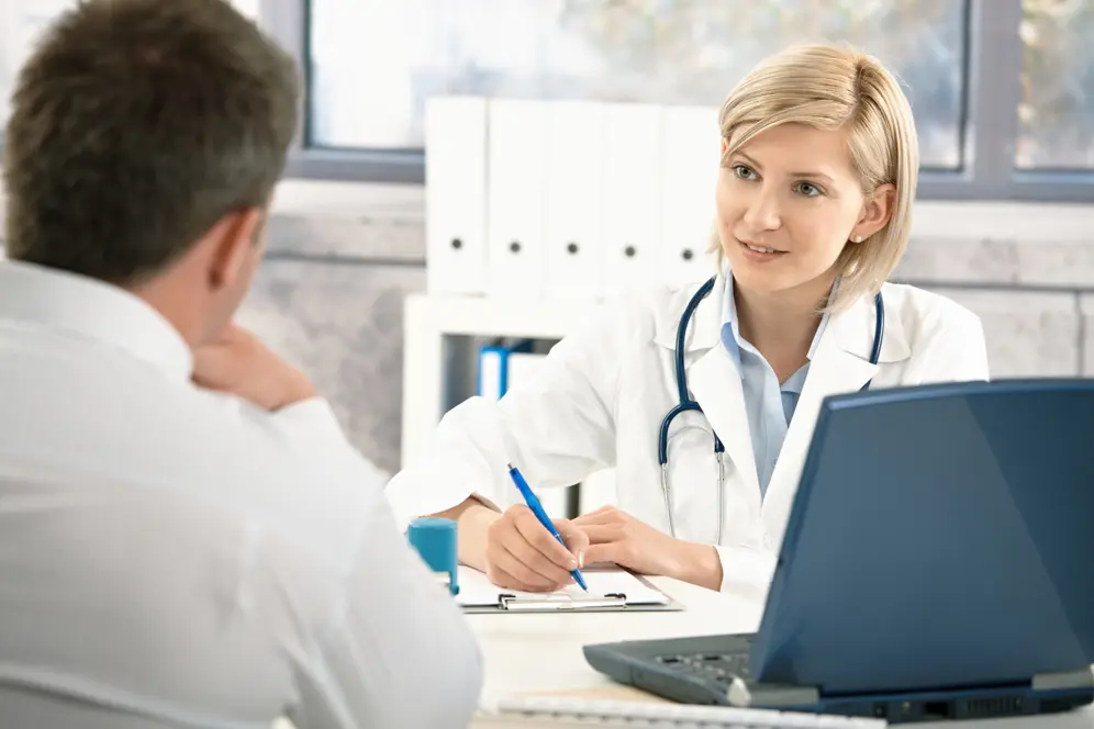Consultation médicale en cabinet, une femme médecin assise à un bureau échange avec un patient et rédige une ordonnance.