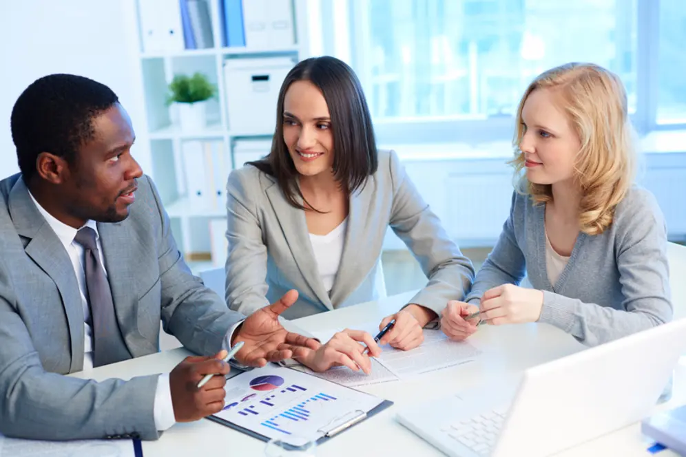 Apprentie travaillant en entreprise dans le secteur du commerce et échangeant avec des collègues lors d'une réunion.
