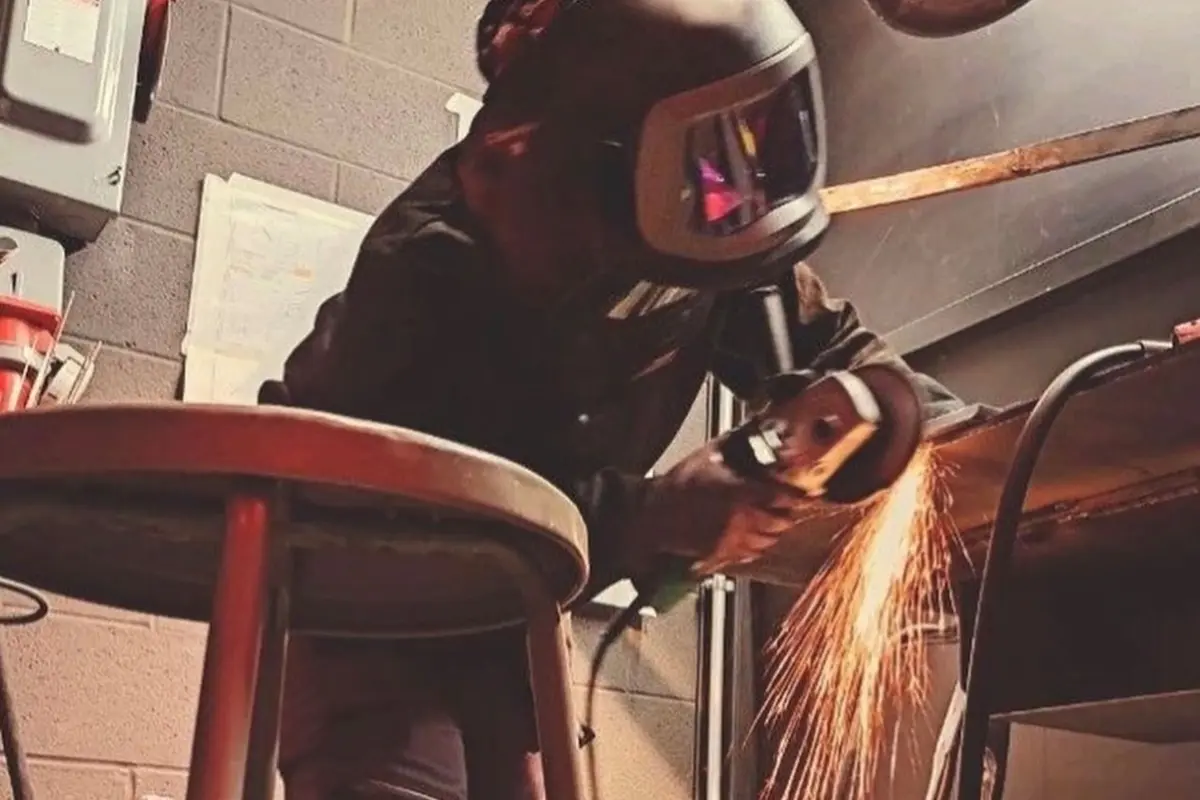 Jeune soudeuse en travaux de meulage en atelier