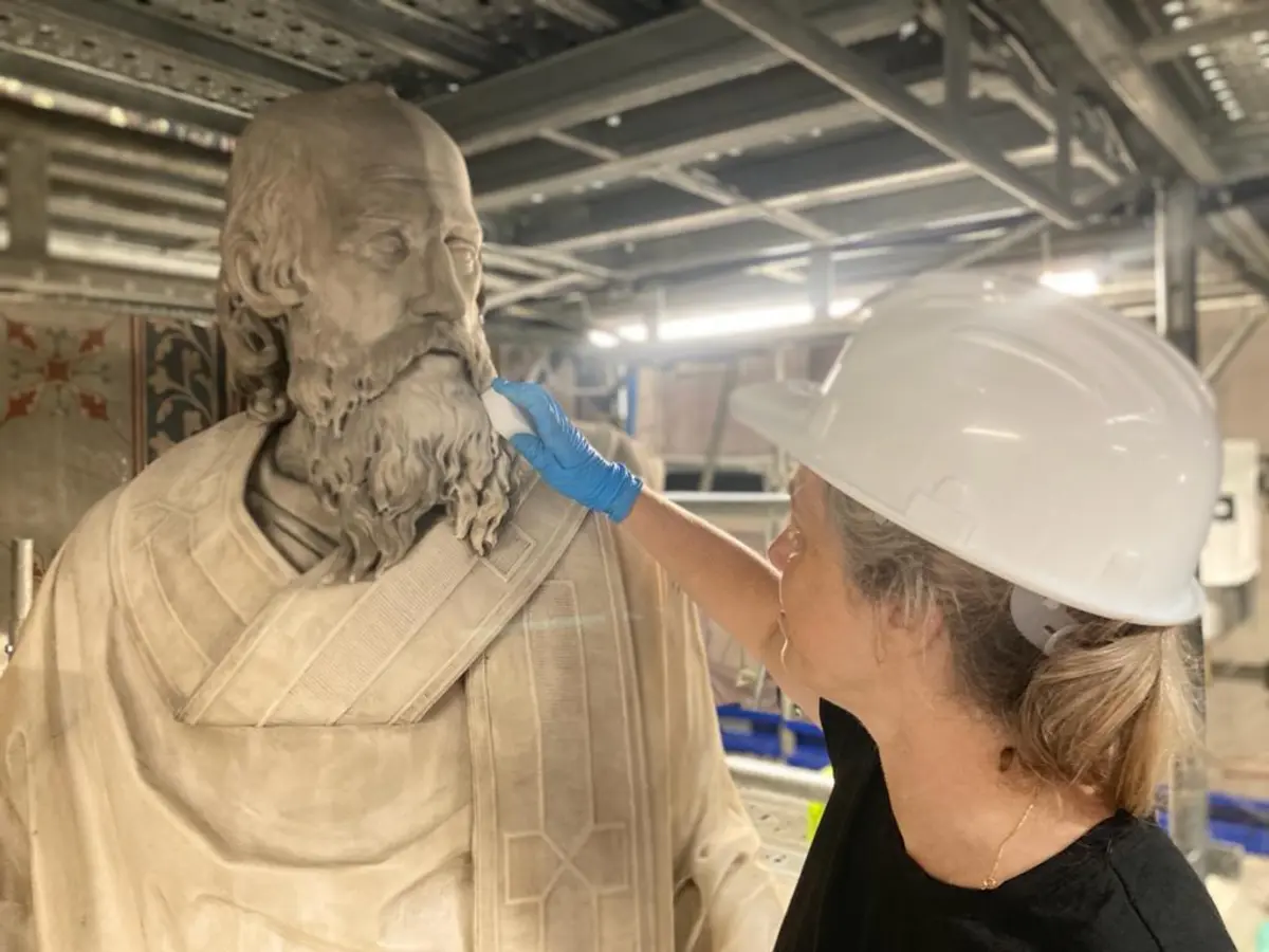 Casqu&eacute;e, la restauratrice d'art nettoie la statue repr&eacute;sentant un homme barbu