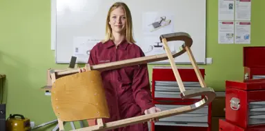Kim porte dans ses mains une chaise design&eacute;e