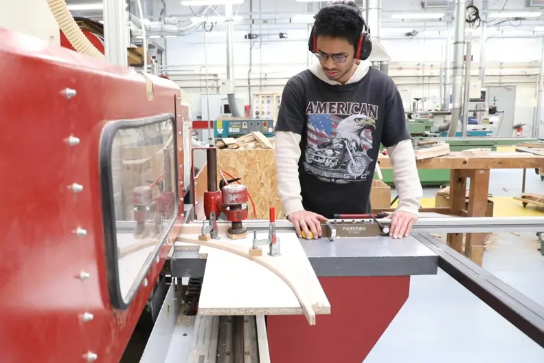 Un &eacute;leve utilise une machine de d&eacute;coupe de bois