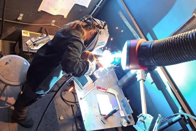 Jeune soudeuse en atelier de soudage prot&eacute;g&eacute;e des rayonnements lumineux
