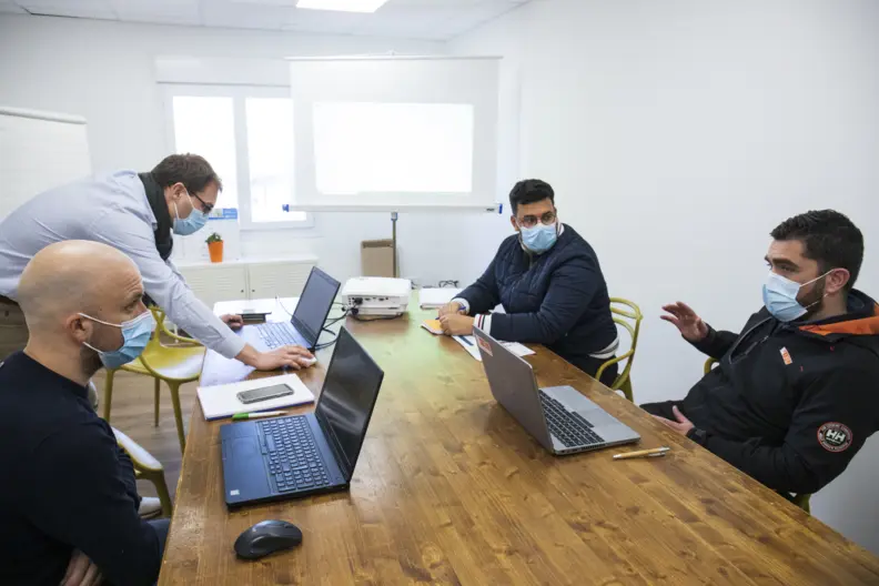 Le directeur et l&rsquo;ensemble des &eacute;quipes discutent autour d'une table sur laquelle sont pos&eacute;s des ordinateurs portables ouverts.