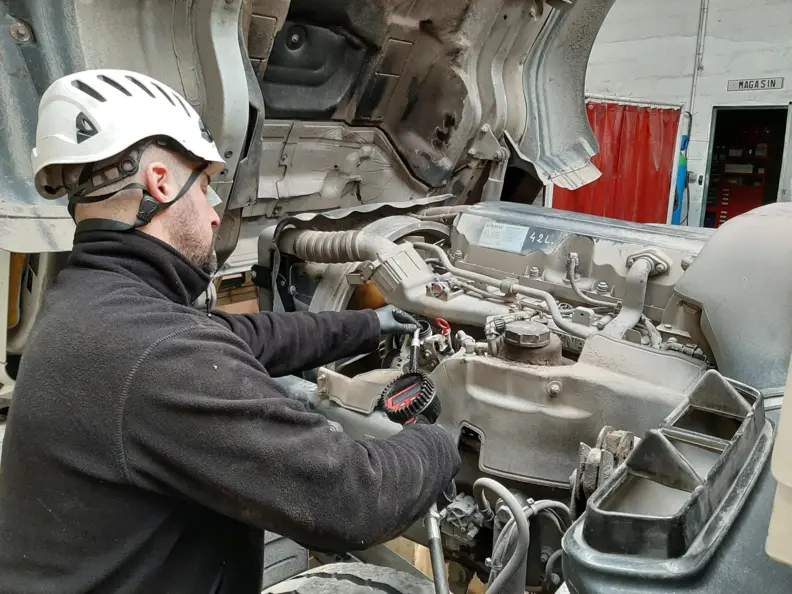 Un m&eacute;canicien d'engins de chantier travaille sur un moteur