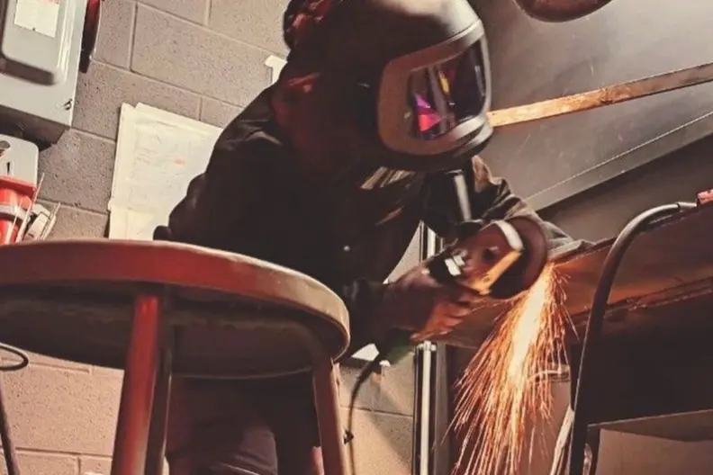 Jeune soudeuse en travaux de meulage en atelier