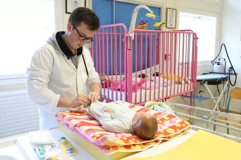 Un &eacute;l&egrave;ve habille une poup&eacute;e