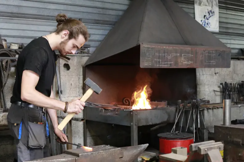 Le ferronnier marteau en main pr&ecirc;t &agrave; taper sur un objet incandescent