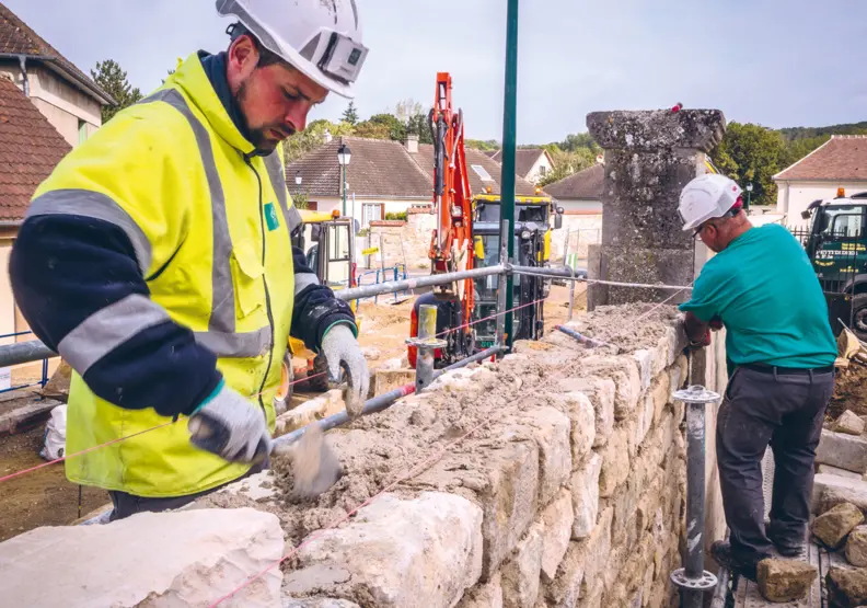 2 ma&ccedil;ons travaillent sur un mur.