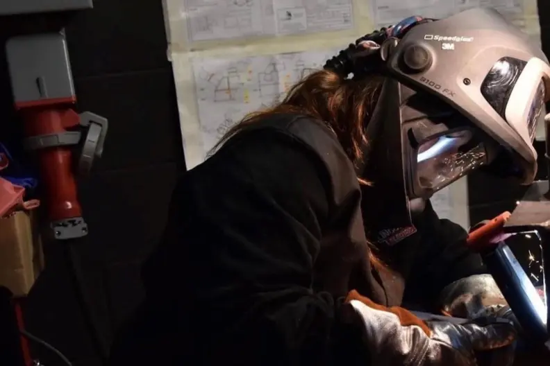 Jeune soudeuse en tenue et &eacute;quipement de soudage en atelier