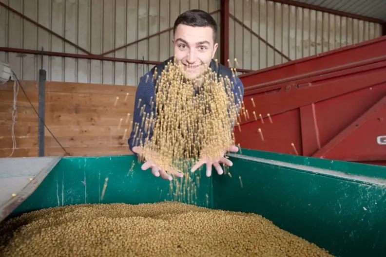 Agriculteur lan&ccedil;ant une poign&eacute;e de c&eacute;r&eacute;ales