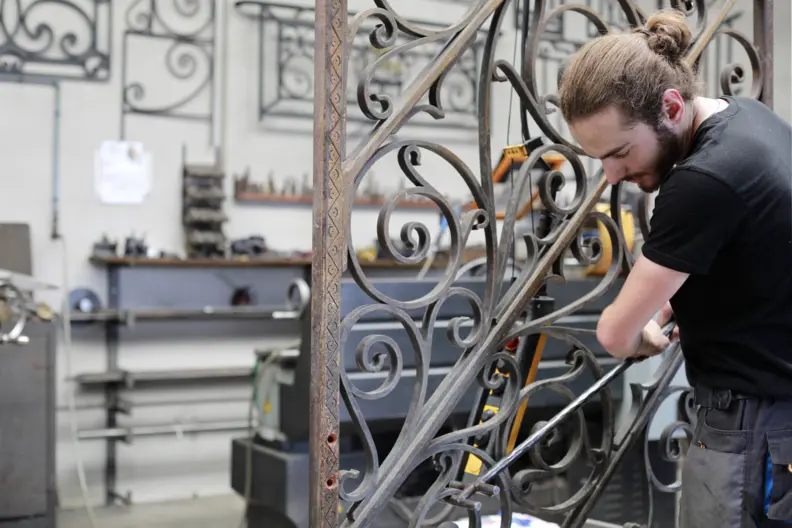 Le ferronnier travaille sur une grille