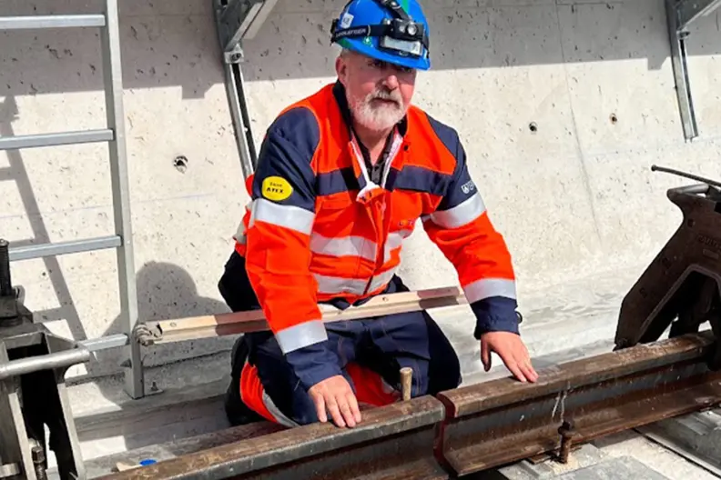 Un soudeur pose devant 2 parties de rail.