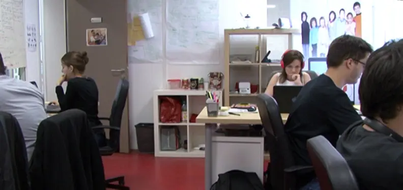 Vur sur l'open space o&ugrave; plusieurs personnes sont assises derri&egrave;re des bureaux.