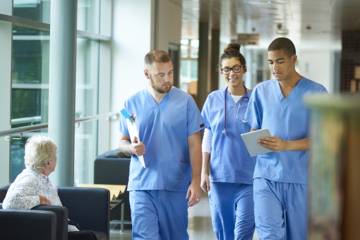 Femme et hommes marchant dans le couloir d'un établissement de santé, de rééducation, ou encore hospitalier.